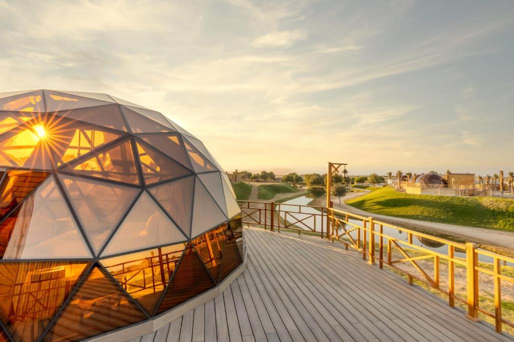ein gewölbtes Gebäude auf einer hölzernen Promenade in der Unterkunft Al Marmoom Oasis Luxury Experiential Desert Domes in Dubai