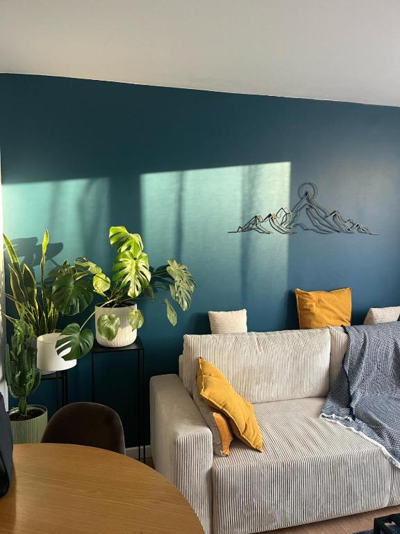 un salon avec un canapé et un mur bleu dans l'établissement Paisible T2, à Villeurbanne