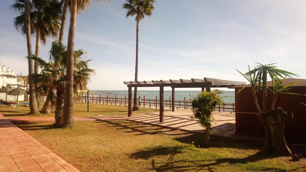 a view of a beach with palm trees and a pavilion at Mansión Alhamar Beachfront in Sitio de Calahonda