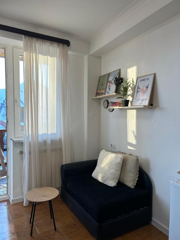 Una sala de estar con un sofá negro y una mesa. en Cozy and Tiny Nest in Gudauri, en Gudauri