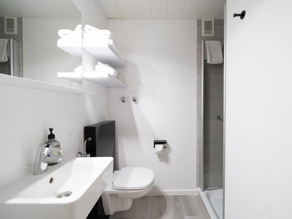 a white bathroom with a toilet and a sink at JustStay Mülheim Hotel & Apartments in Mülheim an der Ruhr