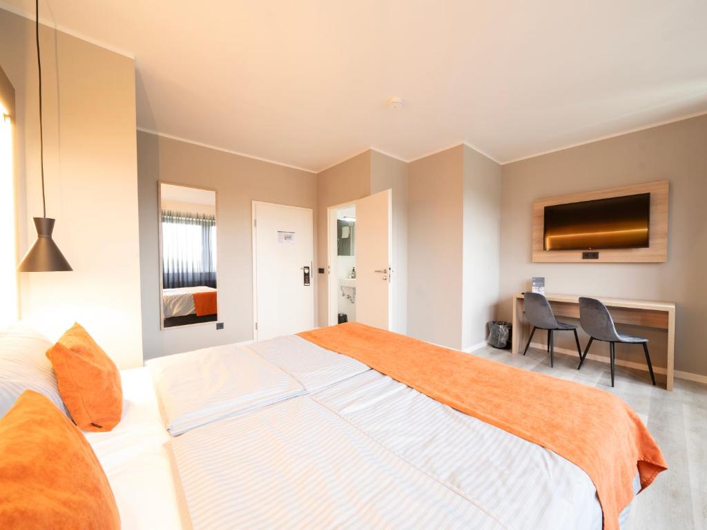 a bedroom with a large bed and a desk at JustStay Mülheim Hotel & Apartments in Mülheim an der Ruhr