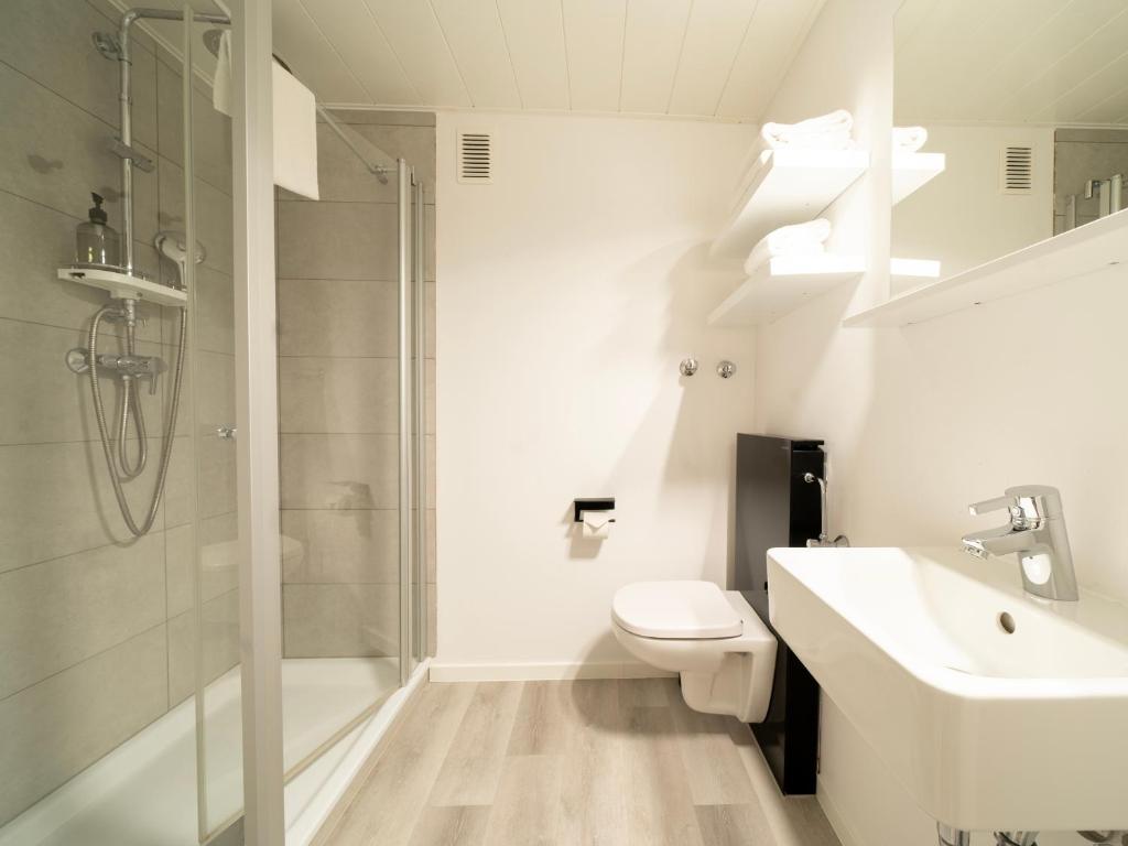 a bathroom with a shower and a toilet and a sink at JustStay Mülheim Hotel & Apartments in Mülheim an der Ruhr
