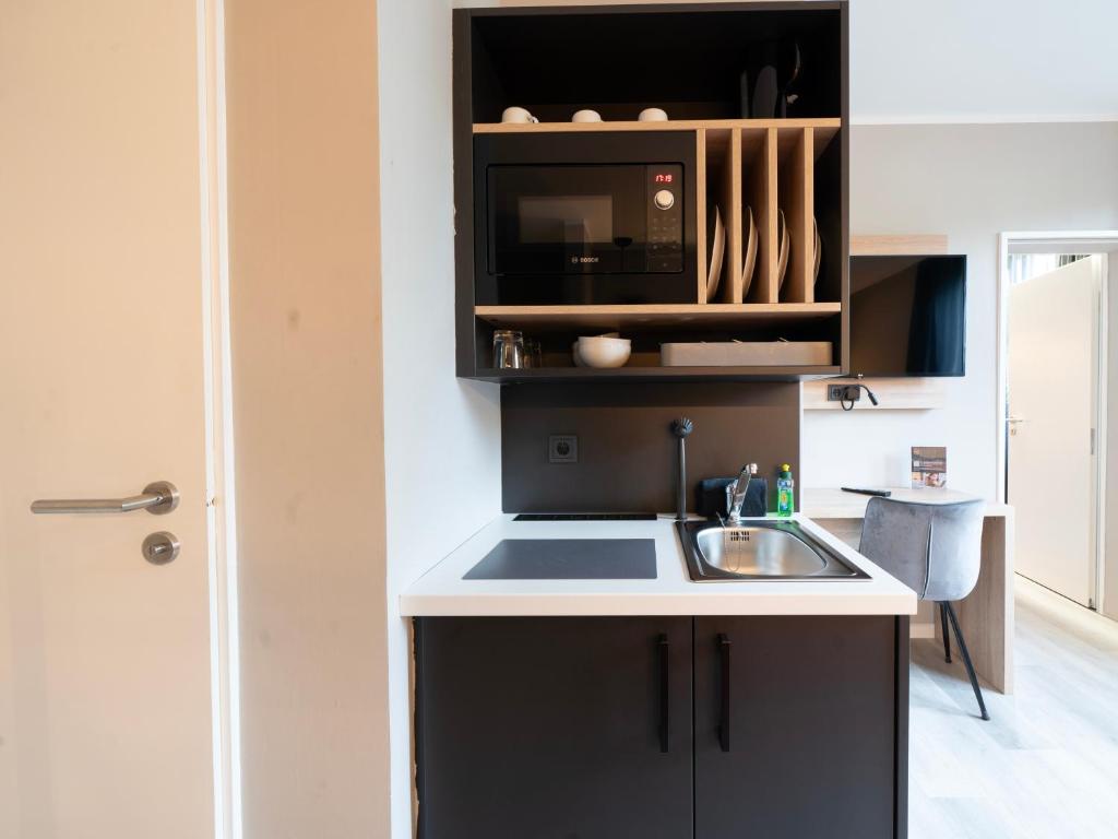 a kitchen with a sink and a microwave at JustStay Mülheim Hotel & Apartments in Mülheim an der Ruhr