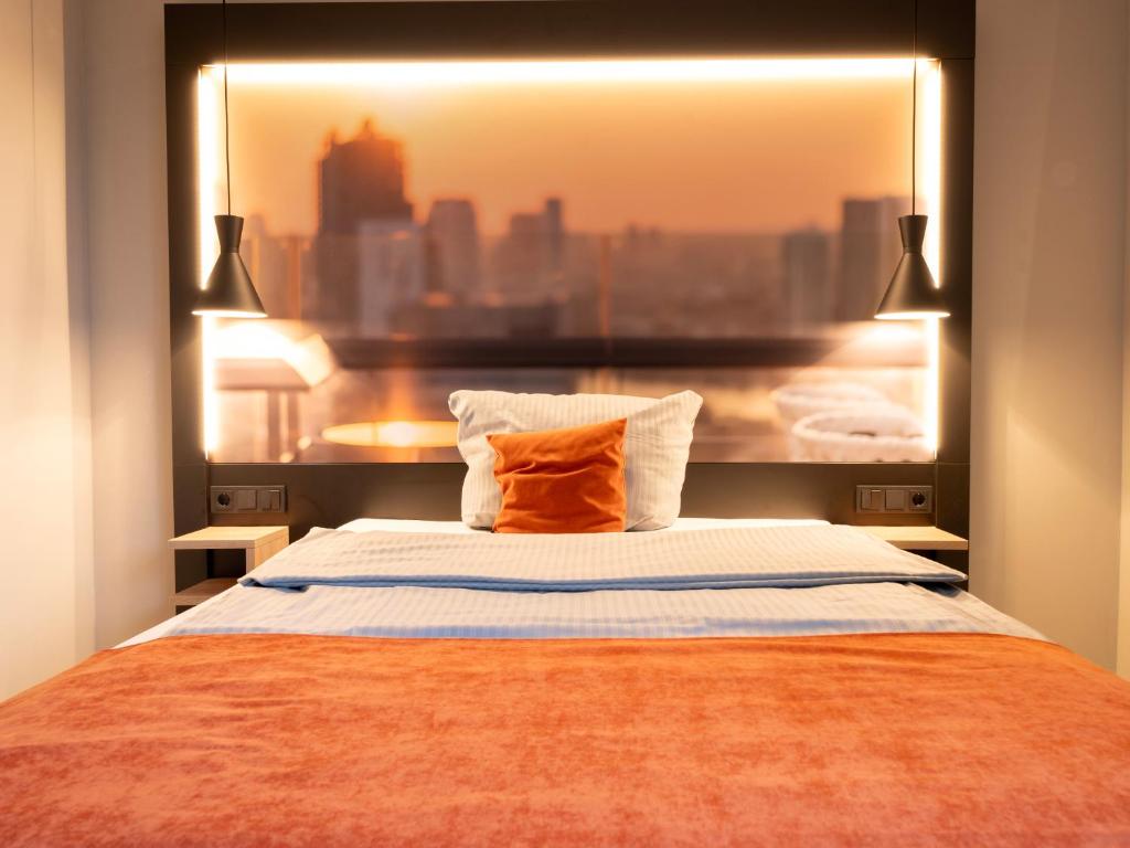 a bedroom with a bed with an orange pillow at JustStay Mülheim Hotel & Apartments in Mülheim an der Ruhr
