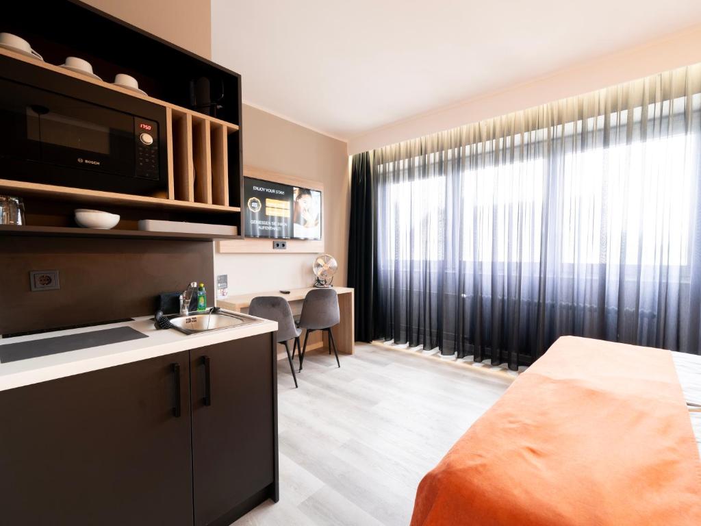 a room with a bed and a kitchen with a window at JustStay Mülheim Hotel & Apartments in Mülheim an der Ruhr