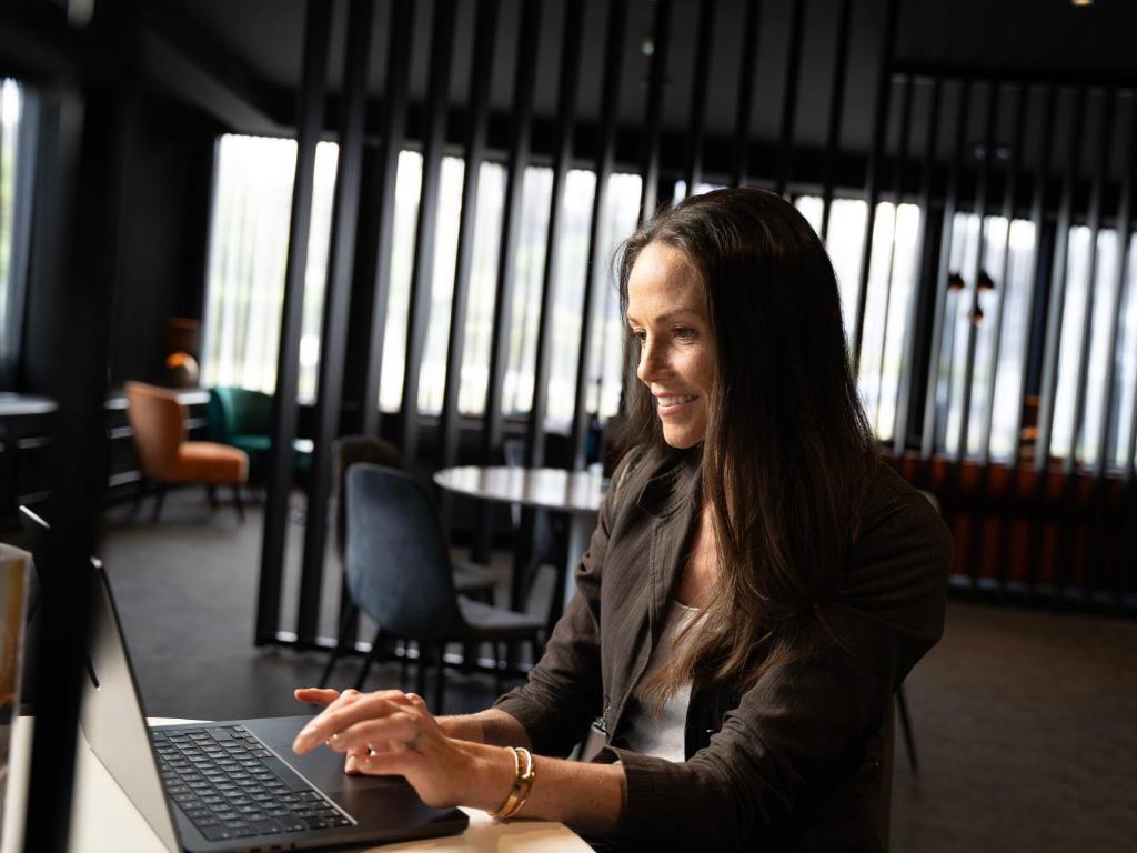 a woman sitting at a desk with a laptop computer at JustStay Mülheim Hotel & Apartments in Mülheim an der Ruhr