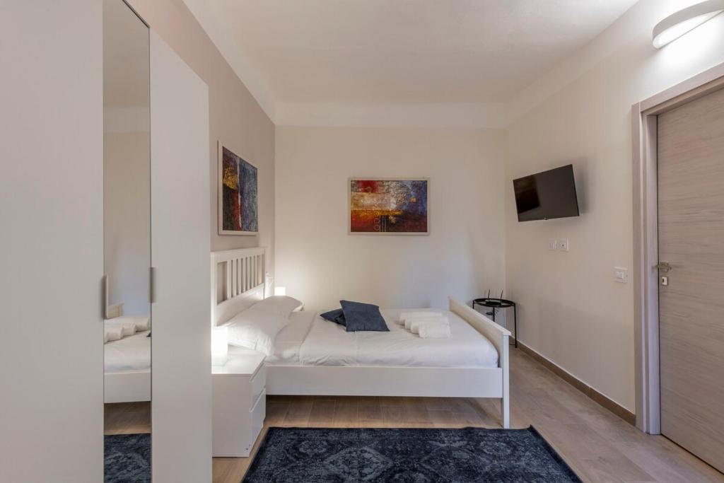 Un dormitorio blanco con una cama y un televisor. en Frisi 3 City Center Suite - B Home, en Milán