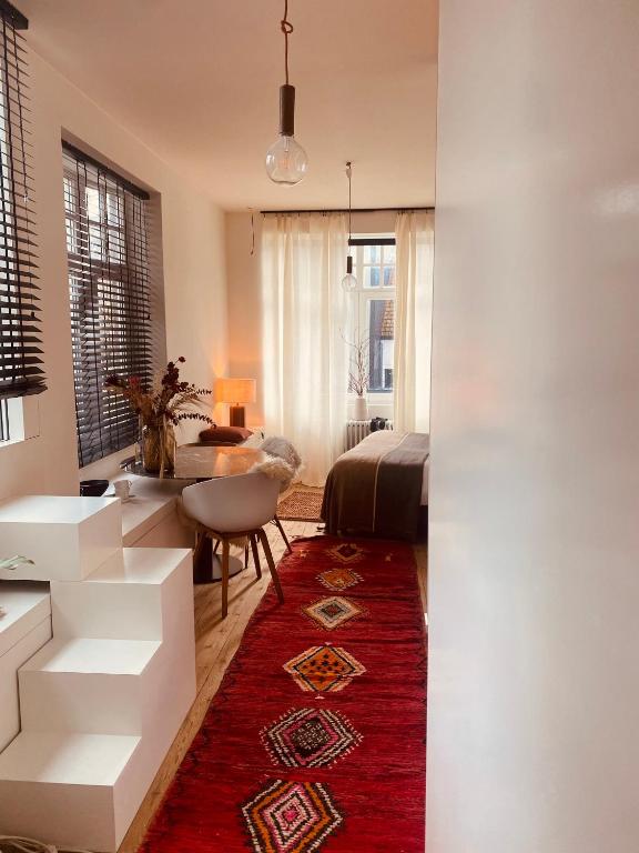 a living room with a red rug and a bedroom at Bohémien garden room in Ghent