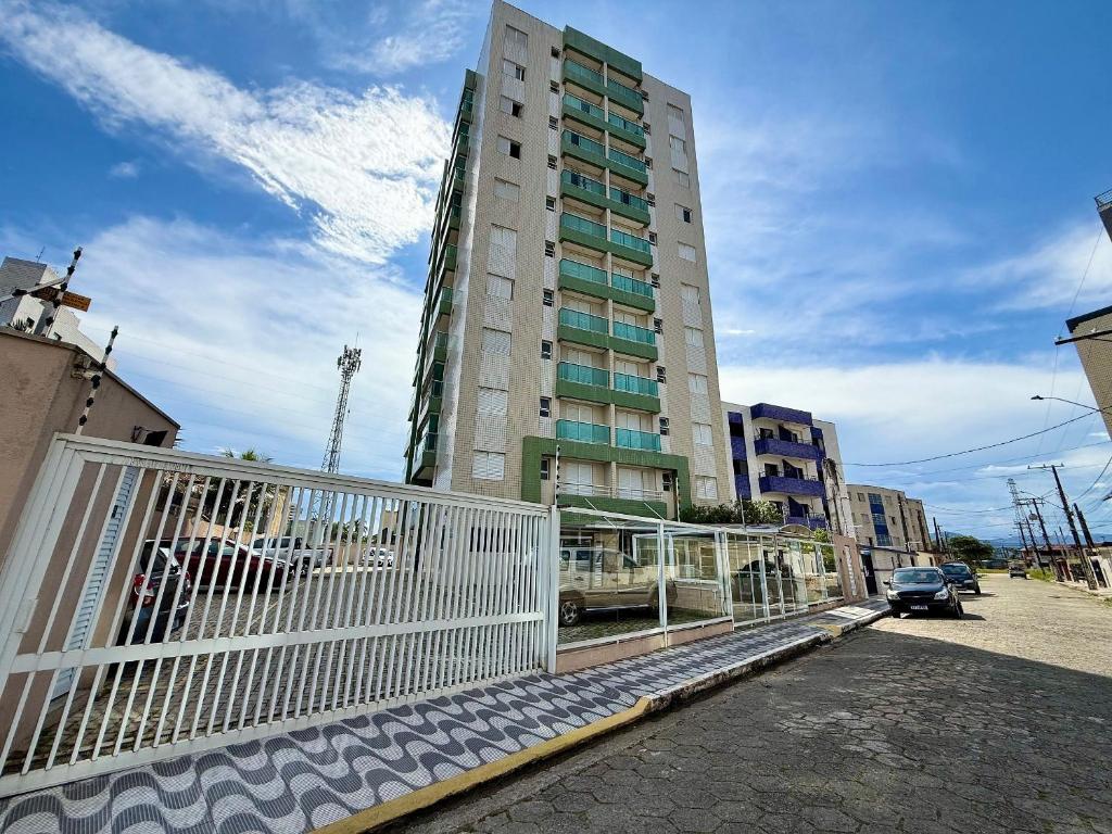 Un edificio alto con una valla blanca delante. en Edifício Baalbek, en Mongaguá