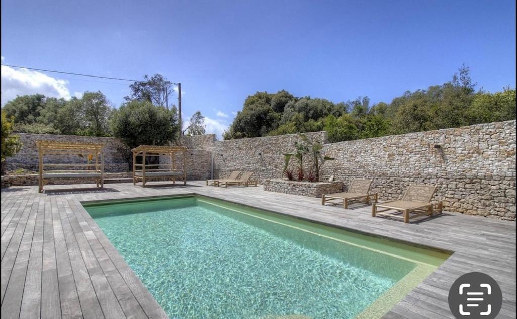 - une piscine en face d'un mur en pierre dans l'établissement Bonifacio Maison 6 personnes Piscine Chauffée, à Bonifacio
