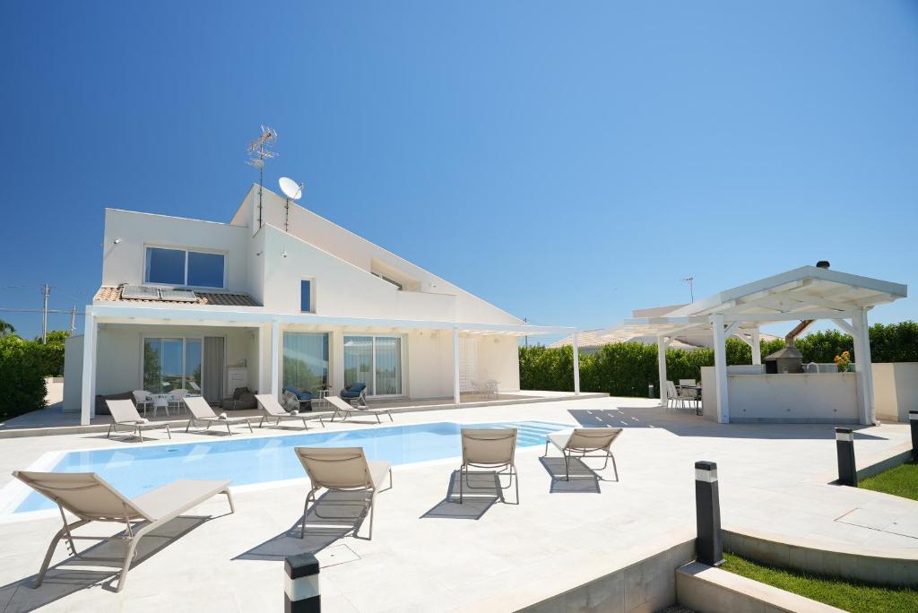 a villa with a swimming pool and chairs at Villa Aria - Modica in Modica