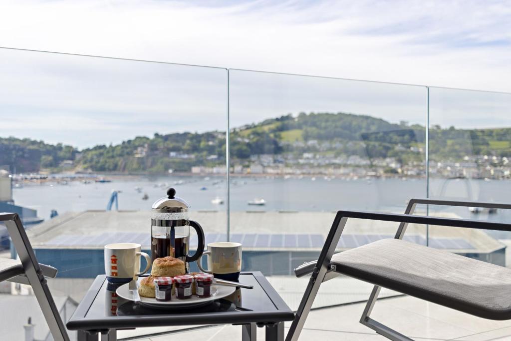 einen Tisch mit einem Wasserkocher und Cupcakes auf dem Balkon in der Unterkunft Teign View, Grand Banks in Teignmouth