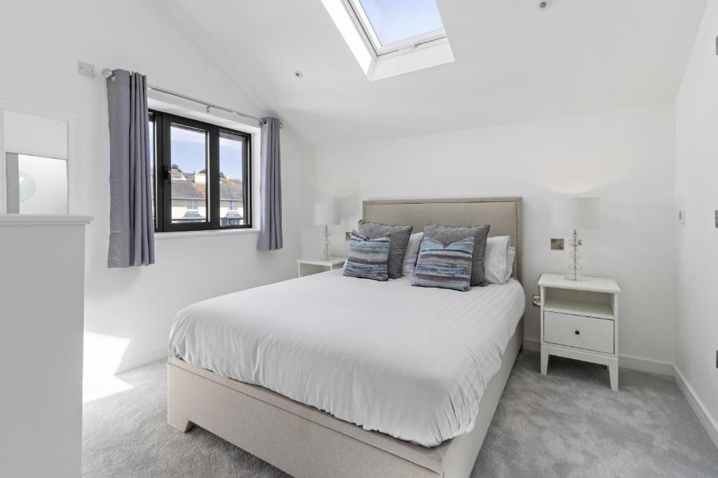 ein weißes Schlafzimmer mit einem Bett und einem Fenster in der Unterkunft Teign View, Grand Banks in Teignmouth
