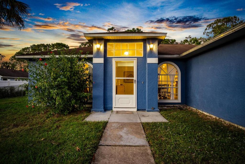una casa azul con una puerta blanca en un patio en Families and large groups, with TVs in every room, en Palm Bay