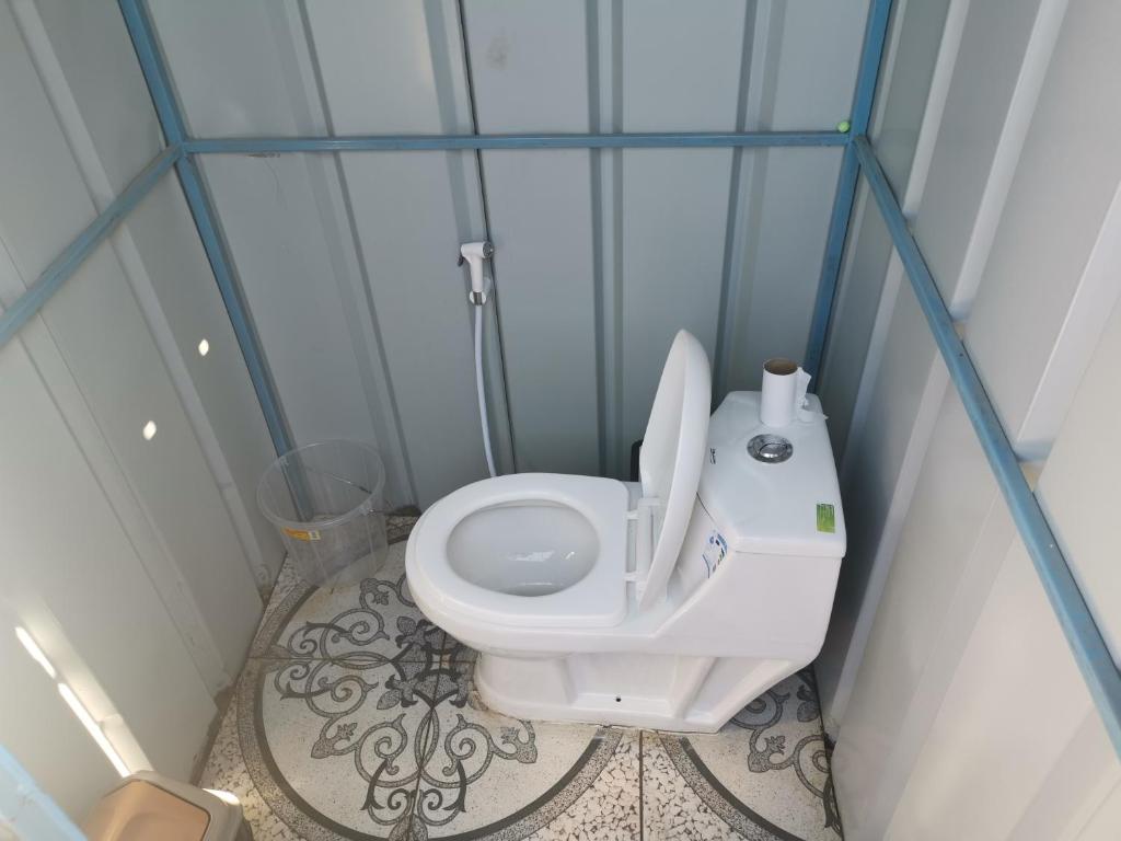 a bathroom with a white toilet in a blue room at ROYAl FINS CAMP in Fins