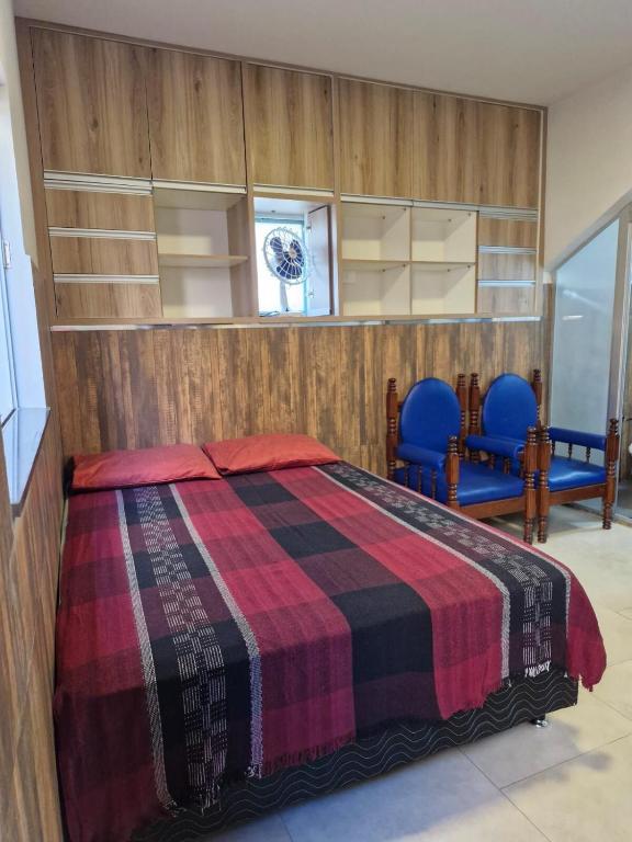 a bedroom with a bed and two blue chairs at Apartamento Studio in Diamantina