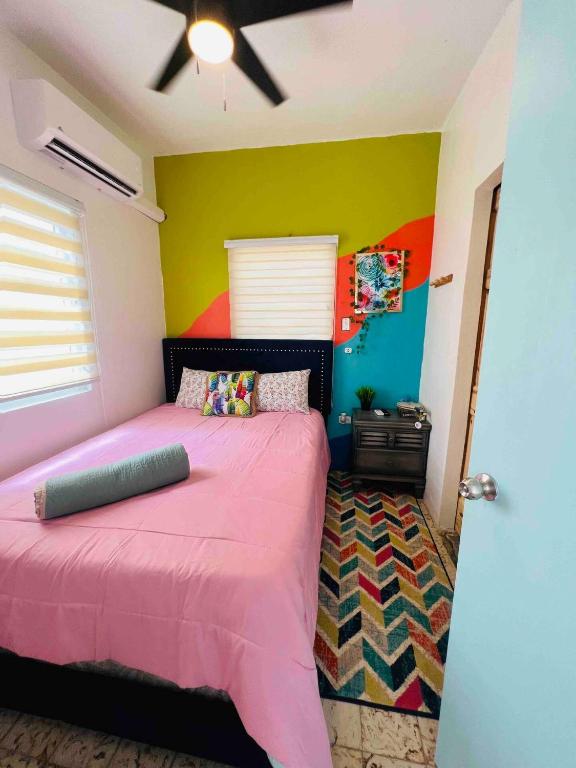 una camera con letto rosa e parete colorata di Isabela Beach Apartment Private Pool a Isabela