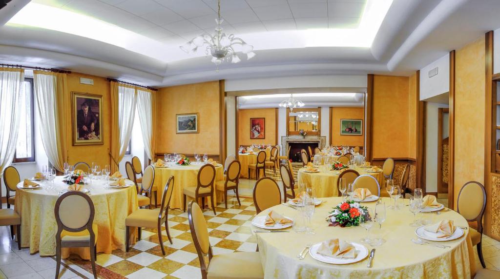 jadalnia ze stołami i krzesłami z żółtymi ścianami w obiekcie Hotel&Ristorante Miramonti Palazzo Storico w mieście Rieti
