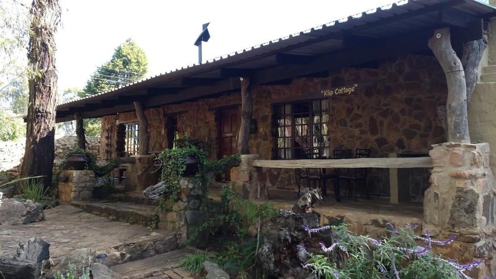 a stone building with a porch and a bird on the roof at Kliphuisjes in Dullstroom