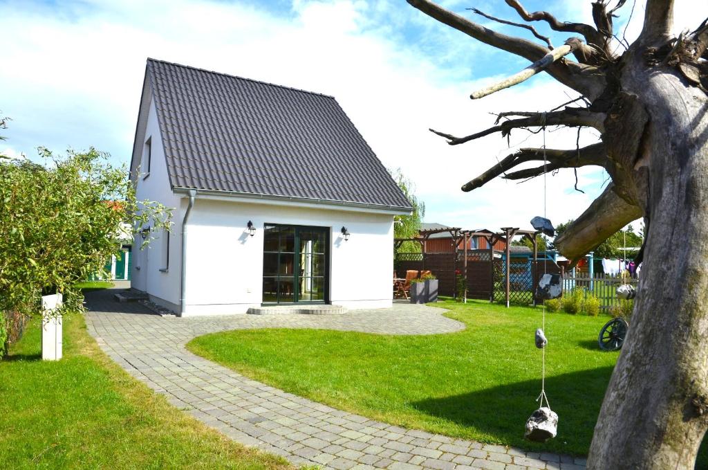 a white house with a tree and a swing at Ferienhaus Lütt Eiland in Polchow