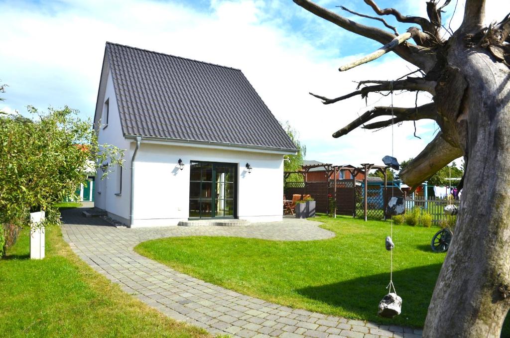 ein weißes Haus mit einem Baum und einer Schaukel in der Unterkunft Ferienhaus Lütt Eiland in Polchow