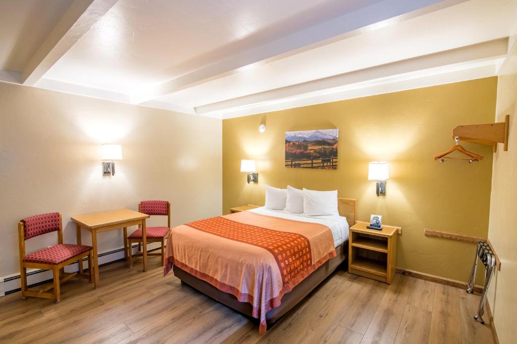 a hotel room with a bed and two chairs at Glenwood Springs Cedar Lodge in Glenwood Springs