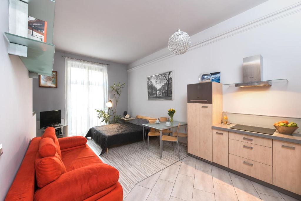 sala de estar con sofá naranja y cocina en Abra 2 Apartments, en Cracovia