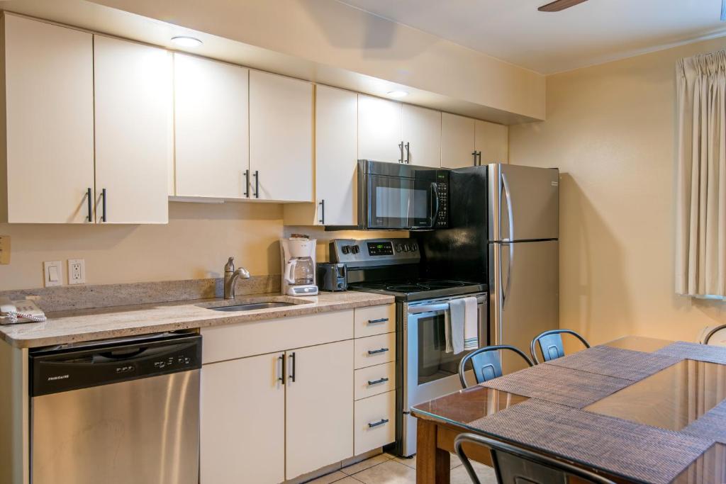 a kitchen with white cabinets and a table with chairs at Glenwood Springs Cedar Lodge in Glenwood Springs