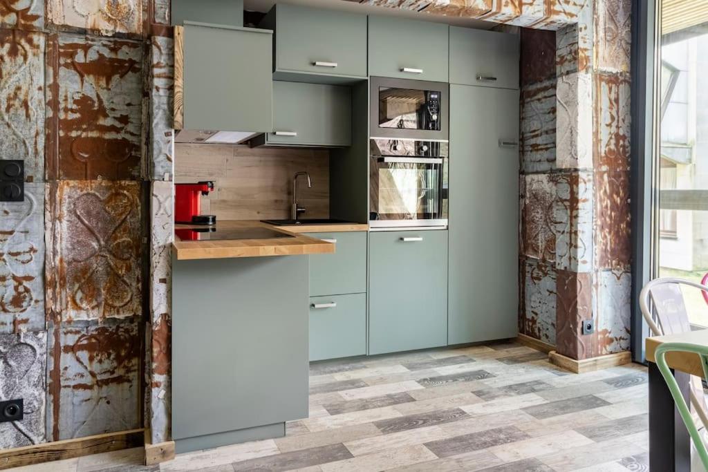 une cuisine avec des placards bleus et un mur en briques dans l'établissement Le BH 22, à La Bresse