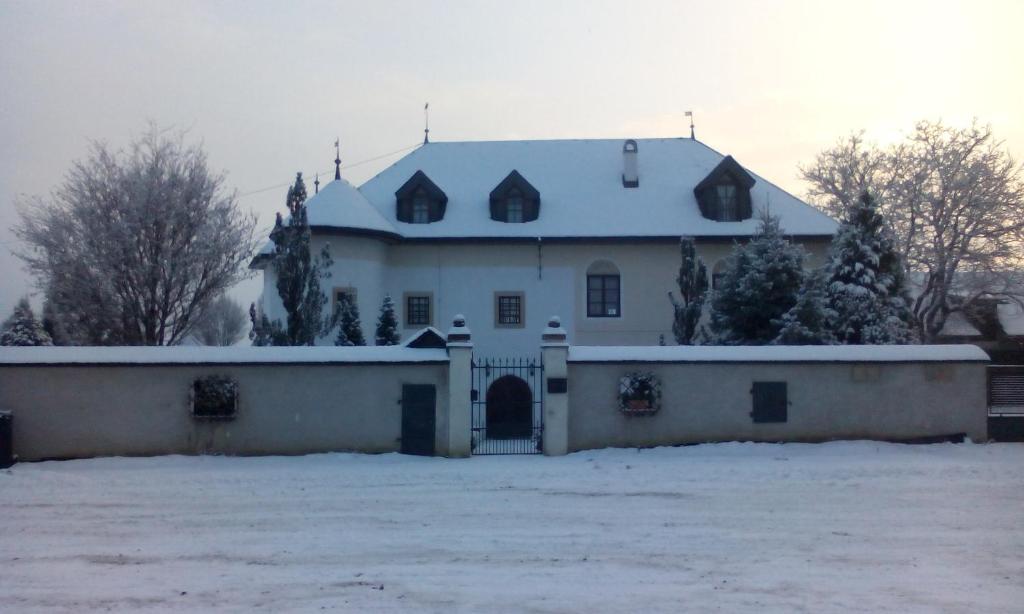 a large white house with a snow covered roof at Castle Kaštieľ Kotešová in Kotešová