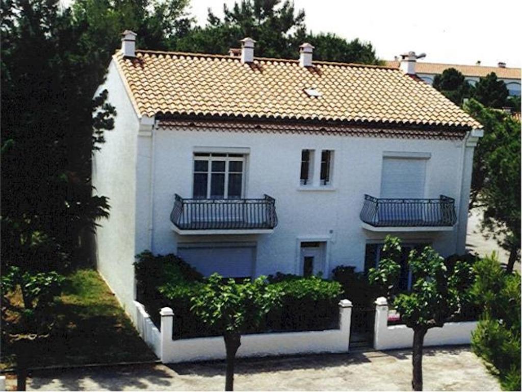 une maison blanche avec un balcon au-dessus dans l'établissement Bel Appartement T3 Climatisé, 50m Plage, Parking - FR-1-776-119, à Argelès-sur-Mer