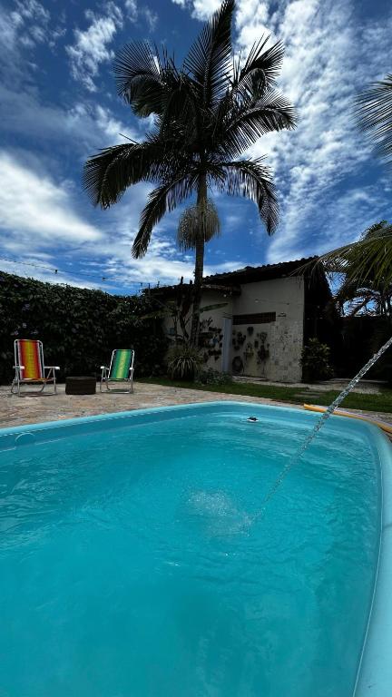 a blue swimming pool with a palm tree in the background at Sossego do Perequê in Ubatuba