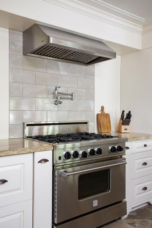 a stainless steel stove in a kitchen with white cabinets at Fairy Bay Lakehouse in Huntsville