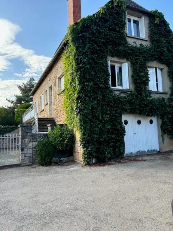 une maison recouverte de lierre avec une porte blanche dans l'établissement Maison confortable près de Bozouls avec jardin, à Bozouls
