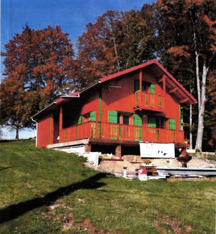 une maison rouge avec une terrasse au-dessus d'un champ dans l'établissement Chalet spacieux avec jardin à La Longeville, à La Longeville