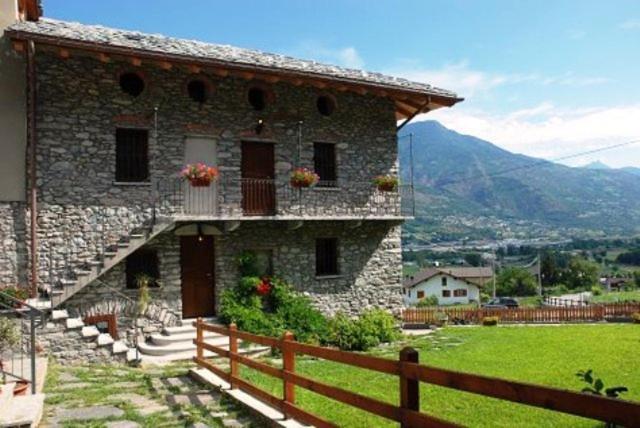 a stone house with a fence in front of it at Affittacamere Il Contadino in Aosta