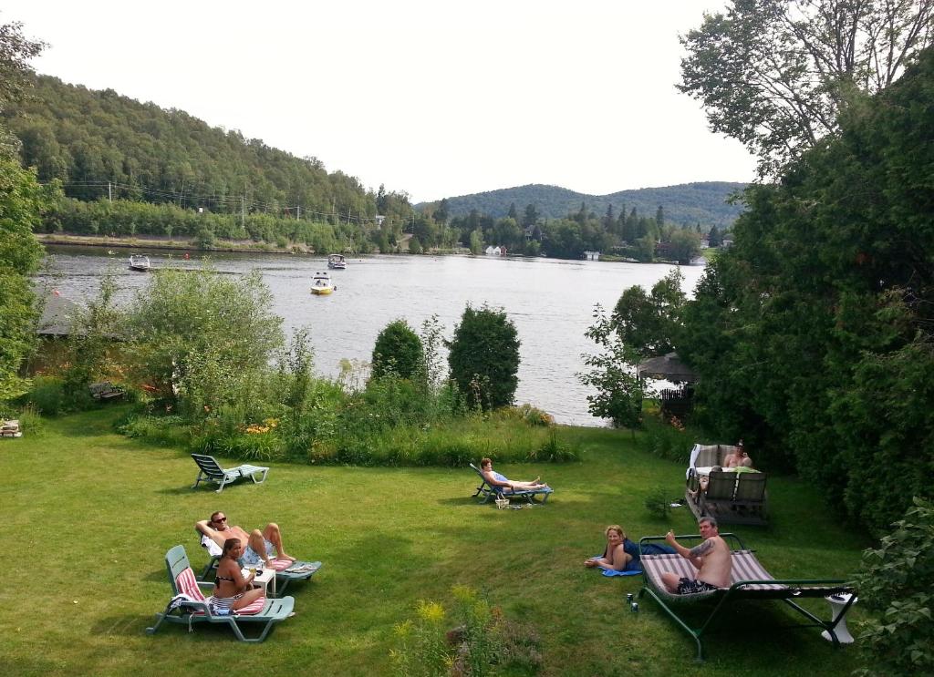 a group of people sitting in chairs on the grass by a lake at Auberge Aux Nuits de Rêve in Sainte-Agathe-des-Monts
