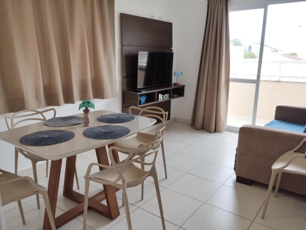 a living room with a table and chairs and a tv at Itaguá - 1 quadra da praia, 2 quartos, 2 banheiros, acomoda 5 pessoas in Ubatuba