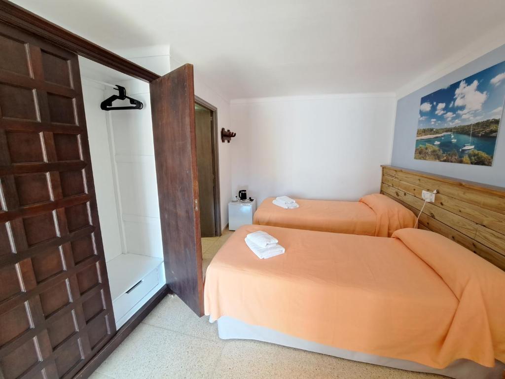 a bedroom with two beds and a wooden door at Hostal Playa in Cala Santanyi