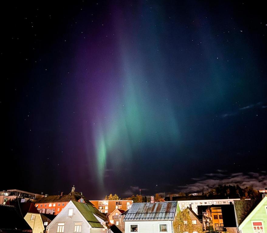 an aurora in the sky over a city with houses at Cozy and Central Loft in Tromsø in Tromsø