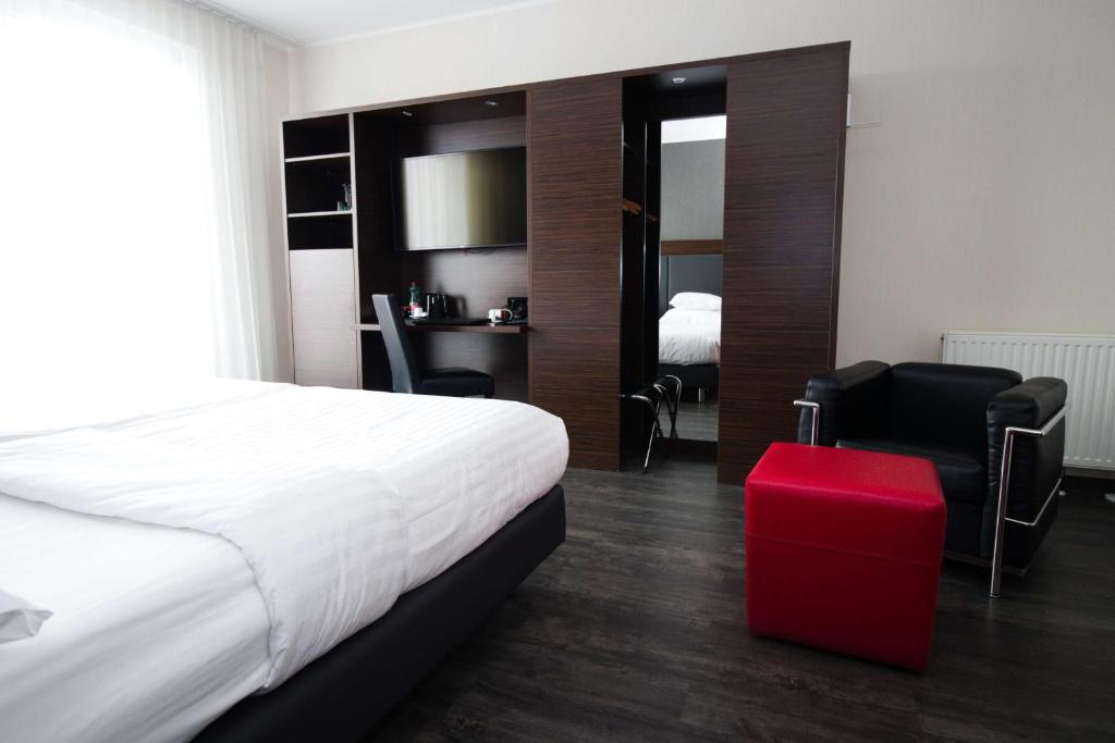 een hotelkamer met een bed en een rode kruk bij Best Western Plus Plaza Hotel Graz in Graz