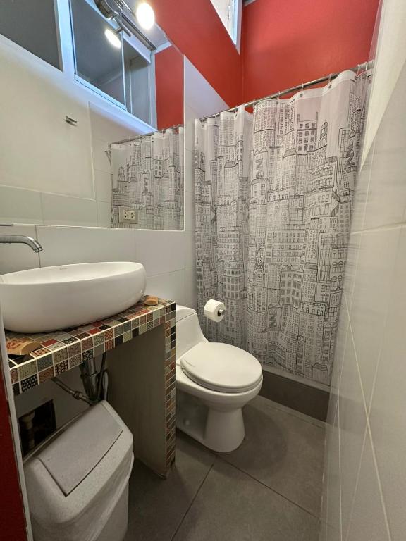e bagno con lavabo, servizi igienici e tenda per la doccia. di Flying Dog Hostel a Lima