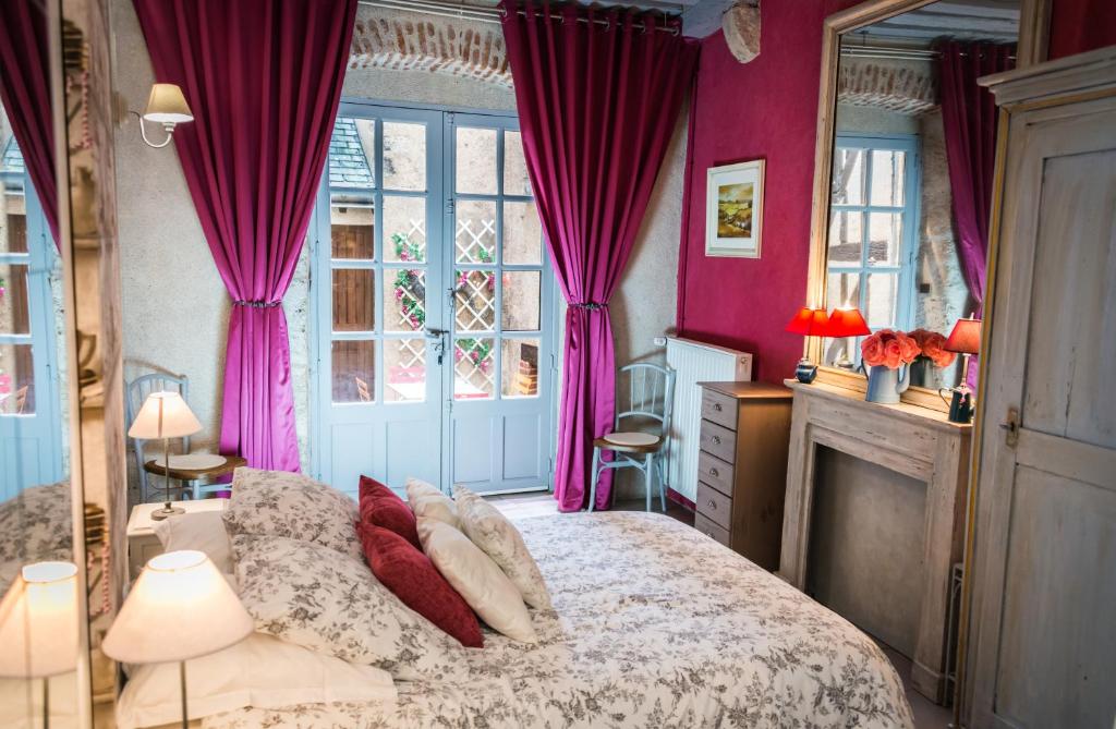 a bedroom with a bed with pink walls and windows at Le Nid De La Loire in Blois