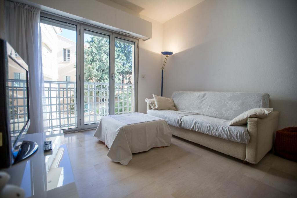 a living room with a couch and a large window at Appartements Villa Rimbaud by Connexion in Cannes