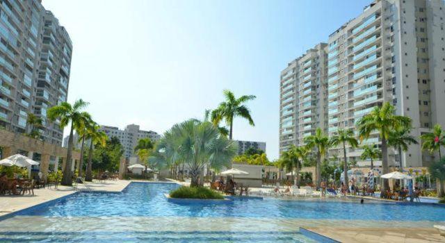 una gran piscina con palmeras y edificios en Apartamento Luxo Barra en Río de Janeiro