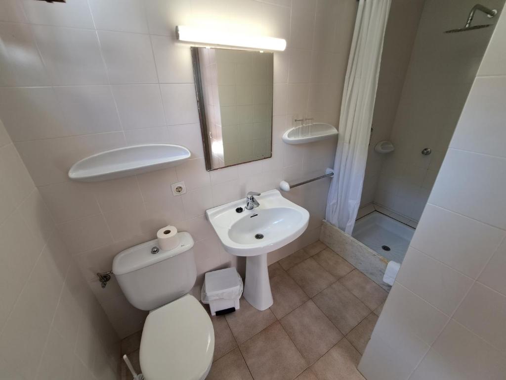 a white bathroom with a toilet and a sink at Hostal Playa in Cala Santanyi