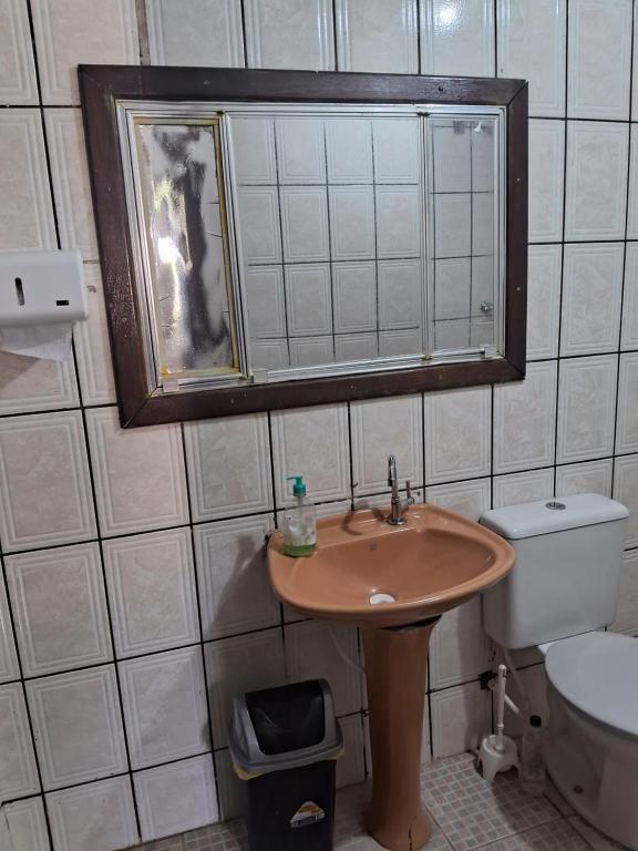 a bathroom with a sink and a toilet and a mirror at Hostel e Pousada Gratiluz in São Thomé das Letras