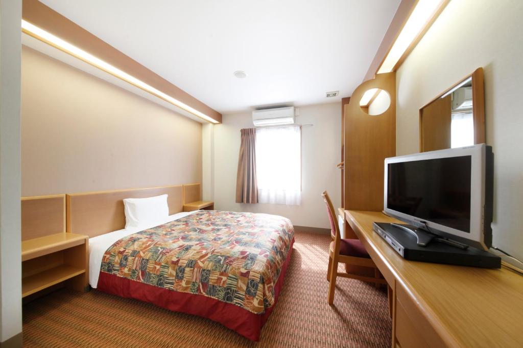 Vessel Hotel Kurashiki في كوراشيكي: غرفة فندقية بسرير وتلفزيون بشاشة مسطحة
