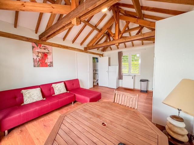 un salon avec un canapé rouge et un parquet dans l'établissement APPARTEMENT "Ti CABANE" villa Bel Kay Nou, à Sainte-Luce